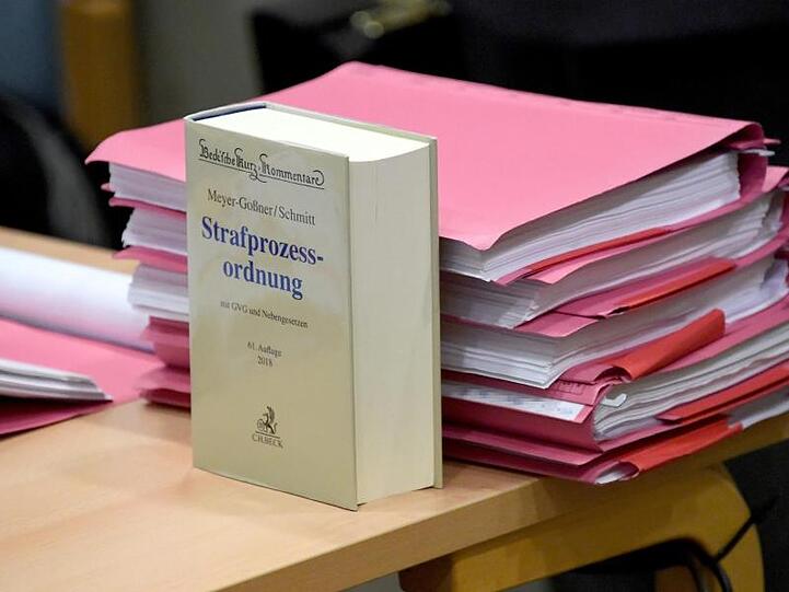 Ein Kommentar zur Strafprozessordnung und Akten liegen auf einem Tisch im Verhandlungssaal. Foto: Carsten Rehder/Archivbild