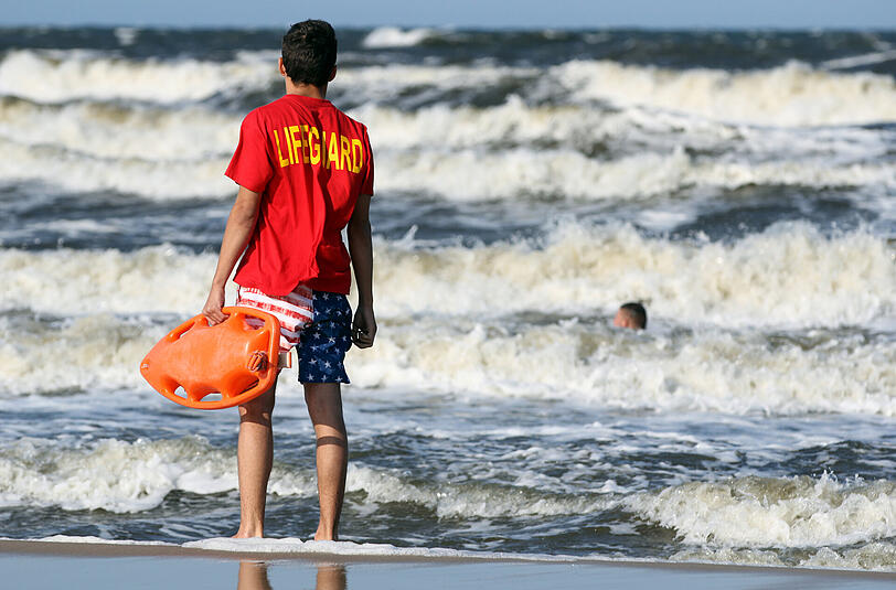 Ein Rettungsschwimmer beobachtet am Strand von Bansin auf Usedom einen Schwimmer. Foto: Tilo Wallrodt/Archiv