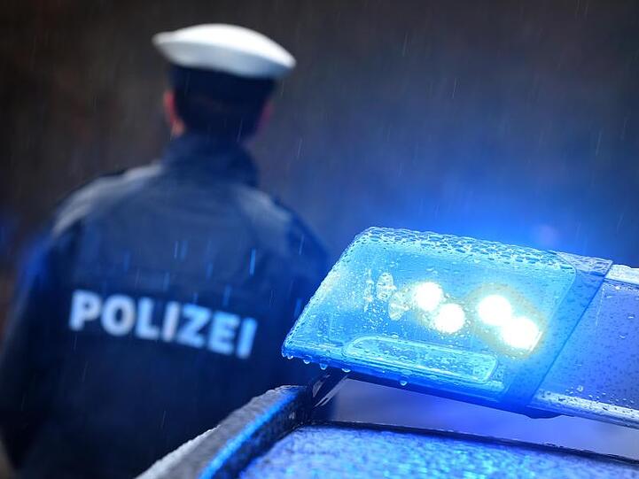 Ein Polizist steht vor einem Streifenwagen dessen Blaulicht leuchtet. Foto: Karl-Josef Hildenbrand/dpa/Archivbild
