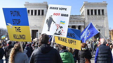 Teilnehmer einer Kundgebung gegen den Krieg in der Ukraine demonstrieren auf dem Königsplatz mit Tafeln mit der Aufschrift "Make Love - Not War" und "Putin stop the Killing!"