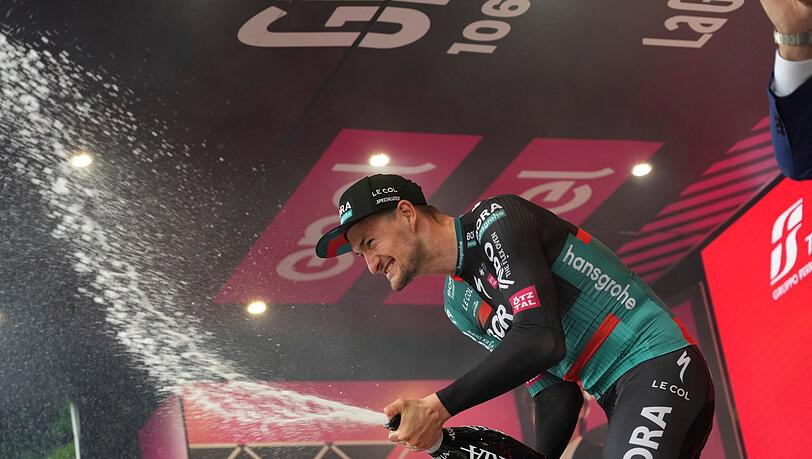 Der deutsche Radprofi Nico Denz vom Team Bora-hansgrohe feiert auf dem Podium seinen Etappensieg.