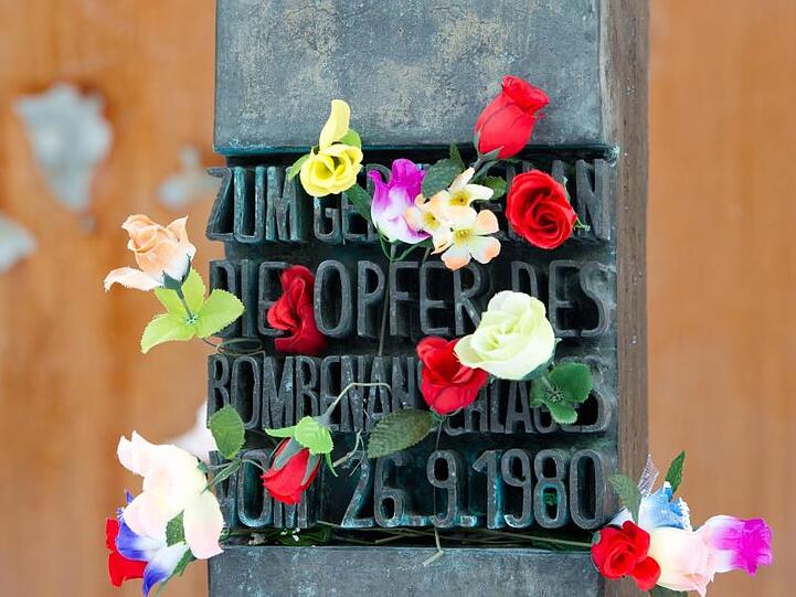 Blumen stecken an einem Denkmal, das an die Opfer des Oktoberfestattentats erinnert. Foto: picture alliance / dpa/Symbolbild