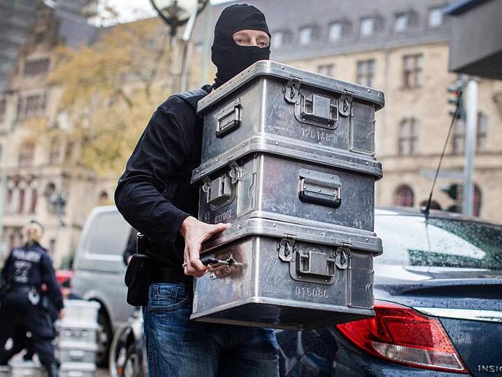 Ein Polizist transportiert Beweismittel ab: "Wir haben einen Fuß in die Tür illegaler Finanzgeschäfte bekommen.".