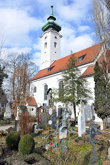 Weiß-blauer Himmel wölbt sich am Dienstag über der Kirche und dem Friedhof Bogenhausen in München.