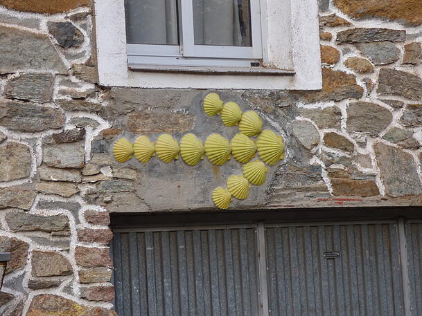 Der Gelbe Pfeil und die Jakobsmuschel sind die Symbole des Jakobsweges und zeigen den Weg nach Santiago de Compostela an. Der Gelbe Pfeil und die Jakobsmuschel sind die Symbole des Jakobsweges und zeigen den Weg nach Santiago de Compostela an.