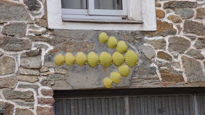 Der Gelbe Pfeil und die Jakobsmuschel sind die Symbole des Jakobsweges und zeigen den Weg nach Santiago de Compostela an. Der Gelbe Pfeil und die Jakobsmuschel sind die Symbole des Jakobsweges und zeigen den Weg nach Santiago de Compostela an.