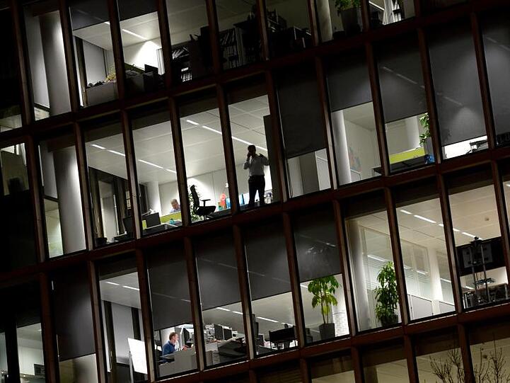 Ein Mann steht am Fenster eines Bürohauses und telefoniert. Foto: Roland Holschneider/Archivbild