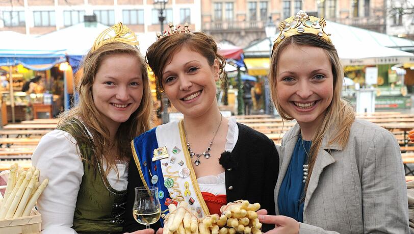 Strahlen gegen das schlechte Wetter an: Spargelkönigin Stefanie Ilmberger (Mitte) mit Schrobenhausener Spargel auf dem Viktualienmarkt, links: Weinprinzessin Christine, rechts: Weinkönigin Marion Strahlen gegen das schlechte Wetter an: Spargelkönigin Stefanie Ilmberger (Mitte) mit Schrobenhausener Spargel auf dem Viktualienmarkt, links: Weinprinzessin Christine, rechts: Weinkönigin Marion