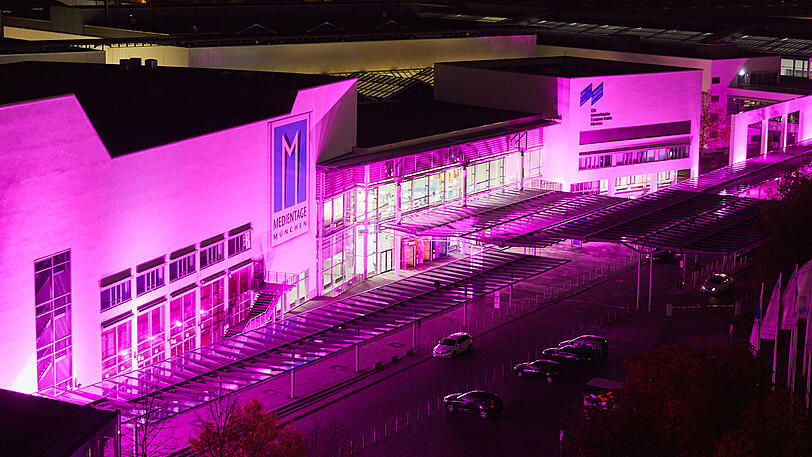 Das Gebäude der Messe München - auch in pinkes Licht gehüllt.