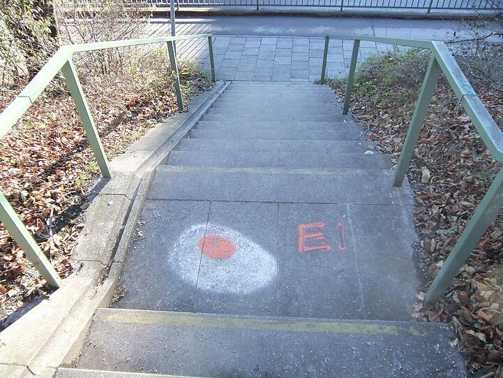 "Ei"-Graffito an der Treppe der kleinen Fußgängerbrücke neben den Gleisen über die Baumgartnerstraße.
