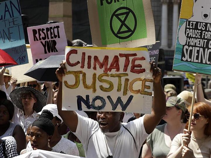 Demonstranten in Johannesburg halten Protestschilder.