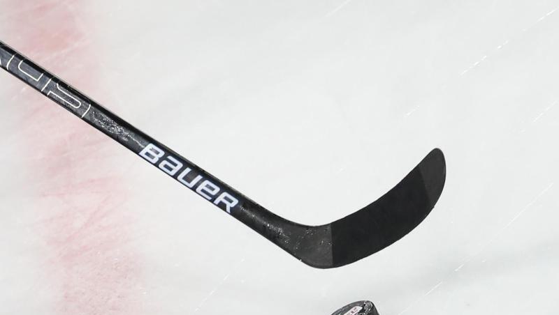 Ein Puck liegt vor einem Eishockey-Schläger auf dem Eis.