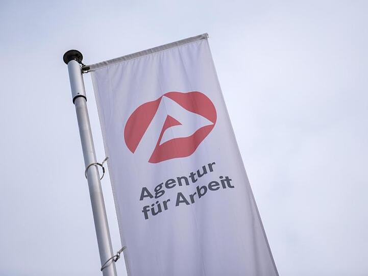 Eine Fahne weht vor der Agentur für Arbeit. Foto: Daniel Bockwoldt/Archiv