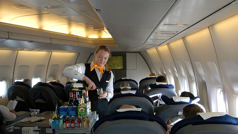 Eine Flugbegleiterin serviert den Passagieren der Business Class Getränke. Eine Flugbegleiterin serviert den Passagieren der Business Class Getränke.