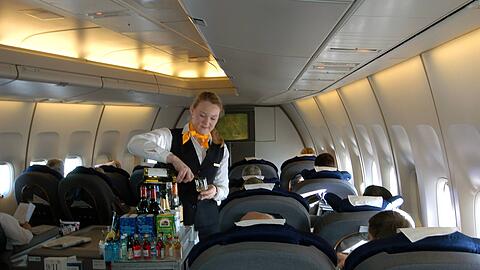 Eine Flugbegleiterin serviert den Passagieren der Business Class Getränke.