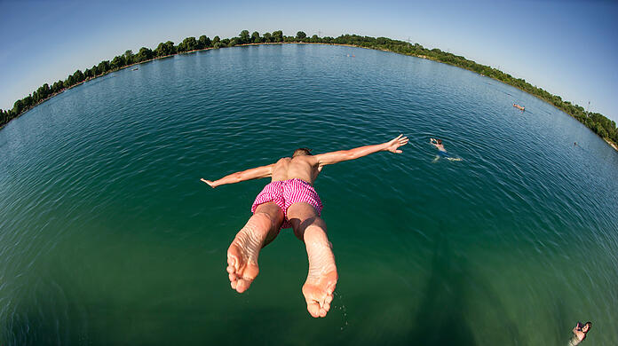 Ein Mann springt vom Ufer des Lußsees ins Wasser. (Archivbild)