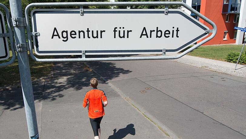 Ein Mann läuft unter einem Schild mit der Aufschrift "Agentur für Arbeit" entlang. Ein Mann läuft unter einem Schild mit der Aufschrift "Agentur für Arbeit" entlang.