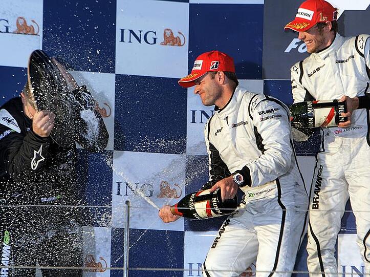 Ross Brawn beweist, dass sich so ein Siegerpokal auch als Schutzschild vor Champagner benutzen kann. Seinen Fahrern Jenson Button (li.) und Rubens Barrichello ist's egal.