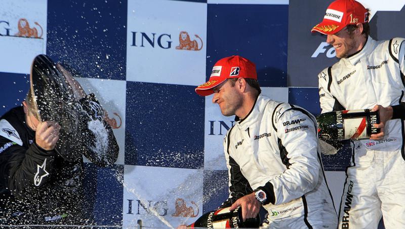 Ross Brawn beweist, dass sich so ein Siegerpokal auch als Schutzschild vor Champagner benutzen kann. Seinen Fahrern Jenson Button (li.) und Rubens Barrichello ist's egal.