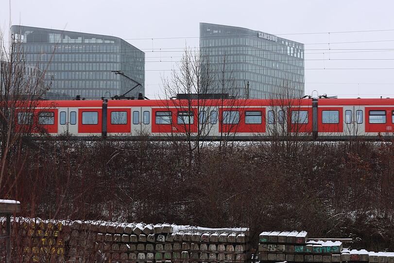 Oben auf dem Damm düst die feuerrote S-Bahn vorbei.