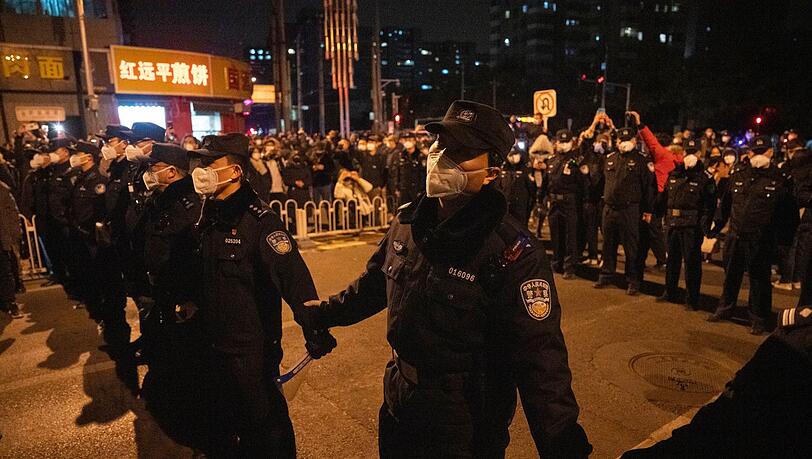 Polizisten bilden eine Linie, um Demonstranten in Peking zu stoppen.