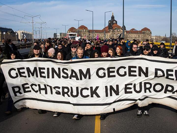 Gegendemonstranten ziehen mit einem Banner durch Dresden.