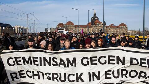 Gegendemonstranten ziehen mit einem Banner durch Dresden.