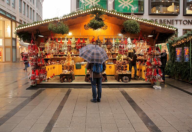 Auch dieser Mann am Münchner Christkindlmarkt scheint noch zu überlegen, ob er sich ins Weihnachtsshopping-Getümmel stürzen soll.