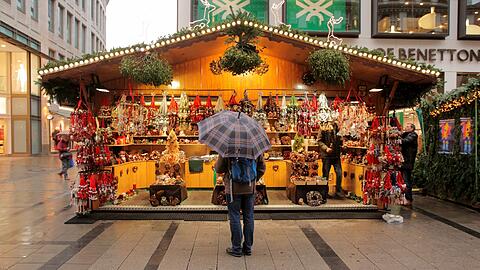 Auch dieser Mann am Münchner Christkindlmarkt scheint noch zu überlegen, ob er sich ins Weihnachtsshopping-Getümmel stürzen soll.