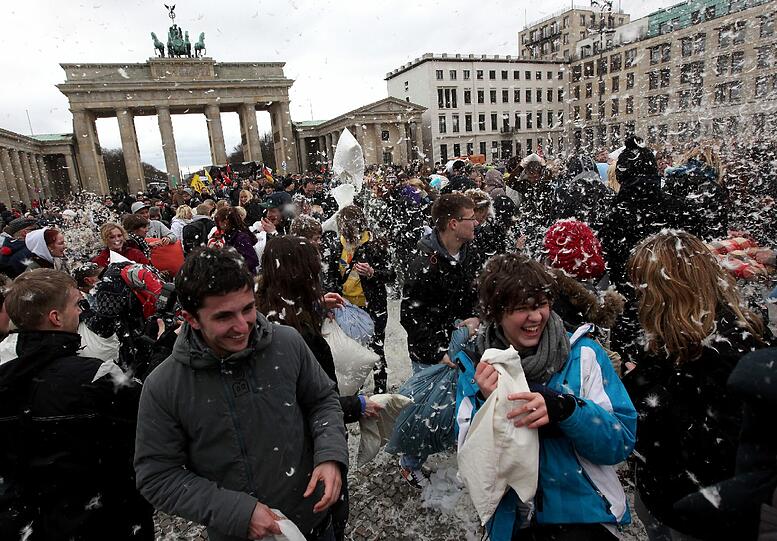 Teilnehmer einer Kissenschlacht schlagen am Samstag (07.04.12) auf dem Pariser Platz in Berlin einander mit Kopfkissen.