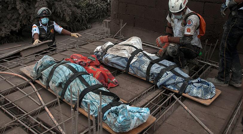Ein Rettungshelfer kniet neben zwei Leichen nach Ausbruch des Feuervulkans. Viele Dorfbewohner hatten wohl keine Chance, als sich der Strom aus Asche, Lava und Gas die Hänge des Berges hinab wälzte.