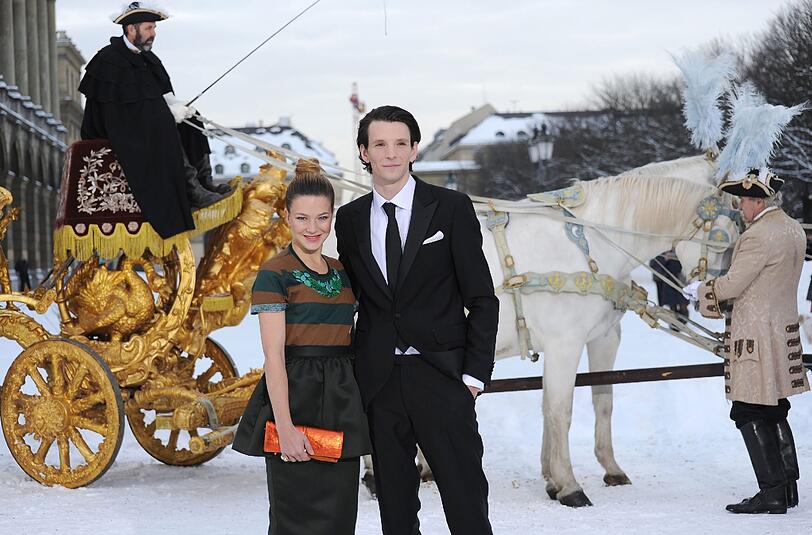 Die Hauptdarsteller Sabin Tambrea (König Ludwig II.) und Hannah Herzsprung (Kaiserin Elisabeth von Österreich) posieren im Hofgarten in München vor der goldenen Kutsche aus dem Film.