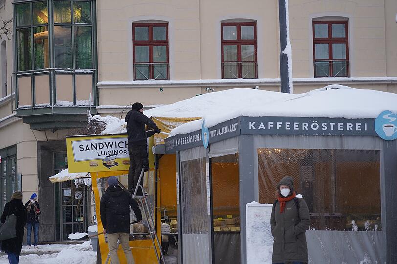 Mitarbeiter der Kaffeerösterei am Viktualienmarkt schaffen den Schnee vom Dach