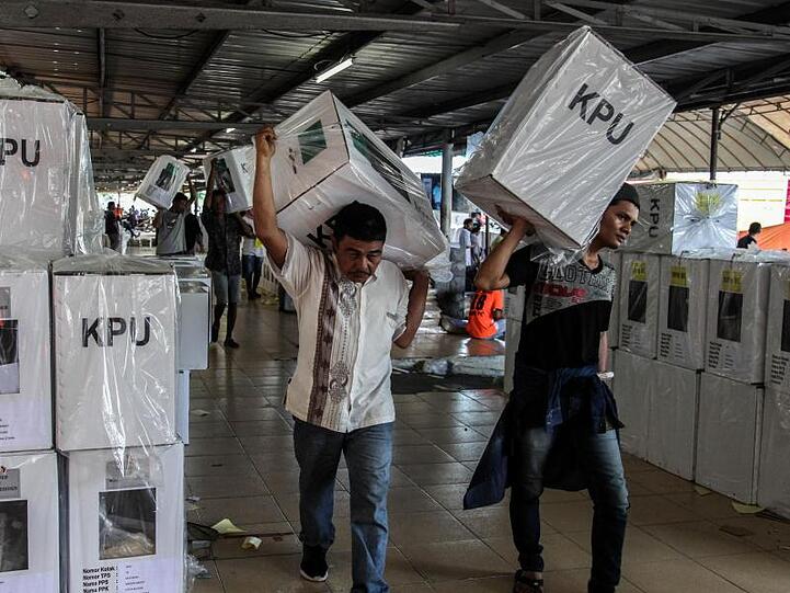 Wahlhelfer tragen Pakete mit Stimmzetteln, die an Wahlstationen verteilt werden.