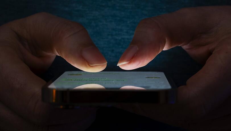 Eine Person liest im Dunklen mehrere Nachrichten auf einem Smartphone. Eine Person liest im Dunklen mehrere Nachrichten auf einem Smartphone.