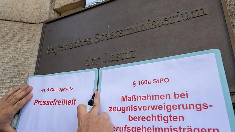 Ein Demonstrant befestigt Auszüge von Gesetzestexten am Eingang zum Justizministerium in München.