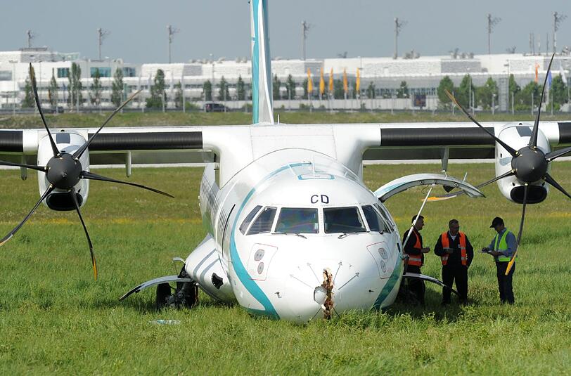 Mitarbeiter des Flughafens in München betrachten die Maschine der italienischen Fluggesellschaft, die am Donnerstag auf dem Münchner Flughafen notlanden musste. Das Flugzeug mit 62 Menschen an Bord hatte kurz nach dem Start in Richtung Venedig umdrehen müssen, weil sich Rauch in der Kabine entwickelt hatte. Bei der Landung wurden fünf Personen leicht verletzt, die Maschine kam neben der Landebahn zum Stehen.