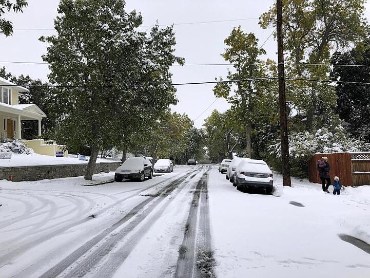 Fußgänger auf einem schneebedeckten Fußweg. Ein Schneesturm hat Teile des US-Bundesstaats Montana lahmgelegt.
