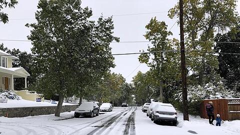 Fußgänger auf einem schneebedeckten Fußweg. Ein Schneesturm hat Teile des US-Bundesstaats Montana lahmgelegt.