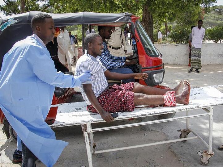 Sanitäter helfen einem Mann, der bei dem Autobombenanschlag in Mogadischu verletzt wurde.