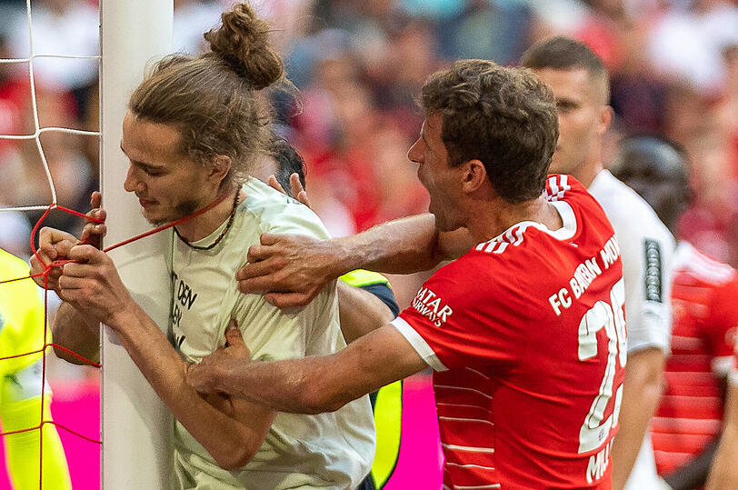 Ein Aktivist will sich beim Spiel der Bayern gegen Gladbach am Tor festketten - Bayernspieler Thomas Müller (r.) versucht ihn abzuhalten.