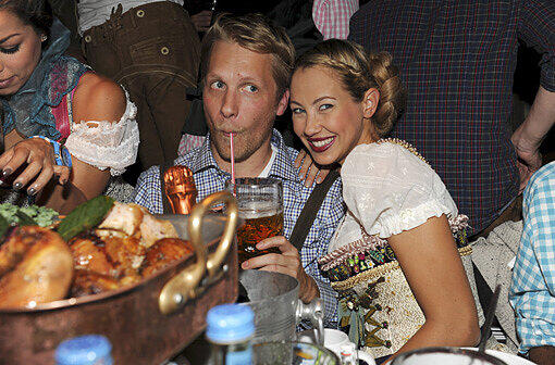 Comedy-Show bei Käfer: Oliver Pocher trinkt sein Bier mit dem Strohhalm, seine Frau Alessandra lächelt und Fernanda Brandao greift nach einem Stück Ente (links).