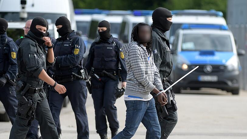 In der Landeserstaufnahmeeinrichtung für Flüchtlinge (LEA) wird ein gefesselter Mann von maskierten Polizisten abgeführt. In der Landeserstaufnahmeeinrichtung für Flüchtlinge (LEA) wird ein gefesselter Mann von maskierten Polizisten abgeführt.