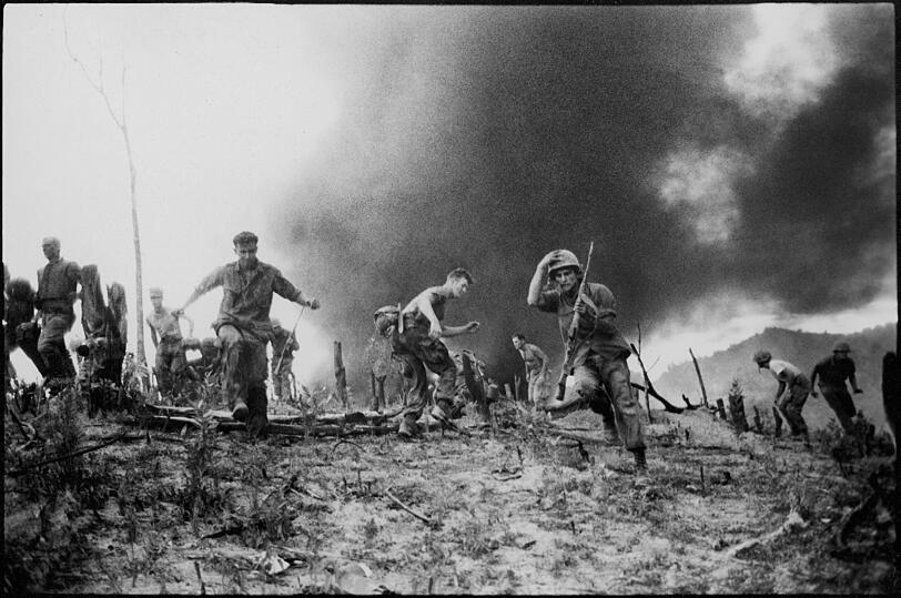 Eindrücklich schildern Faas Bilder die Schrecken des Krieges: US-Marines jagen auseinander, während ein CH-46-Helicopter im Hintergrund brennt, nachdem er nahe der entmilitarisierten Zone zwischen Nord- und Südvietnam abgeschossen wurde.