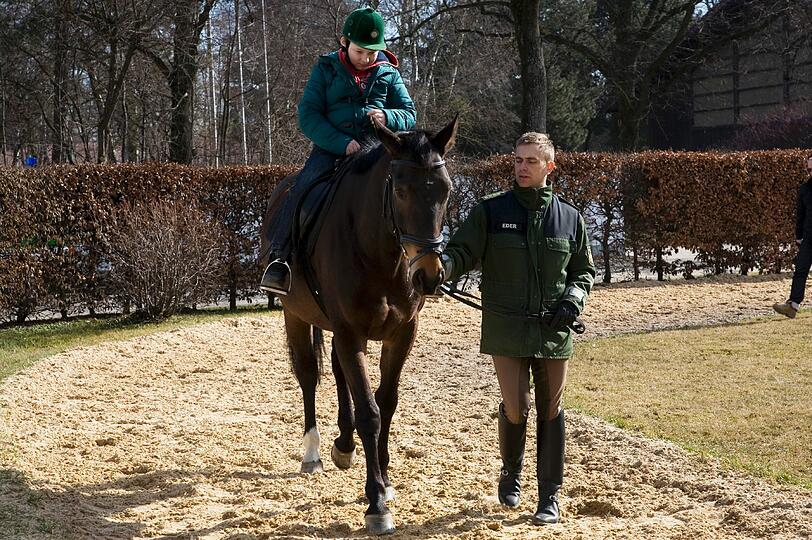 Maxi sitzt zum ersten Mal im Sattel eines Polizeipferds. Reitlehrer Stefan Eder führt Emilio am Zügel.