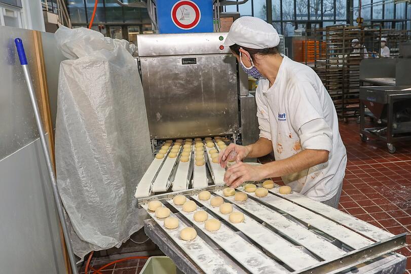 ... diese portioniert den Teig in einzelne Krapfen. Aziz Zavkiev nimmt die rohen Krapfen heraus und lässt sie noch einmal gehen.