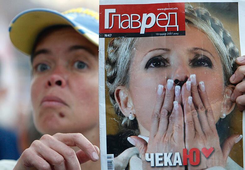 Eine Frau hält das Titelblatt einer Zeitung in die Höhe. Auf dem Cover: Ex-Premier Julia Timoschenko.