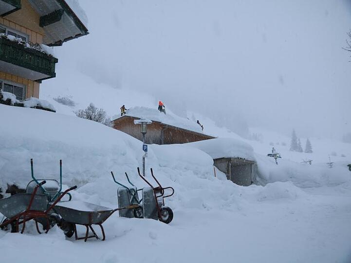 Einsatzkräfte schaufeln Schnee von einem Hausdach. Foto: Benjamin Liss