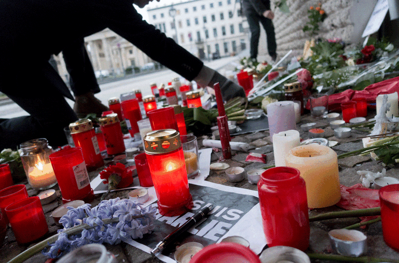 In Berlin legen Pasanten Kerzen und Blumen nieder.