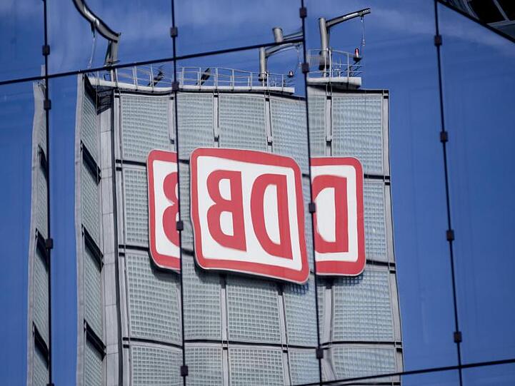 Das Logo der Deutschen Bahn AG spiegelt sich in Berlin in einer Gebäudefassade.